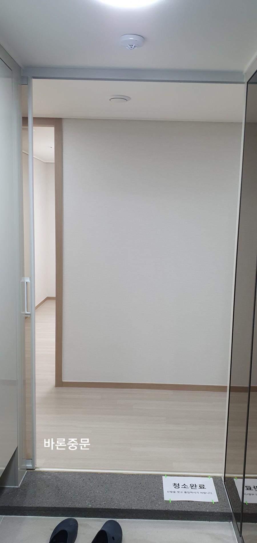 베이지색 벽지와 유리문이 설치된 현관 전경