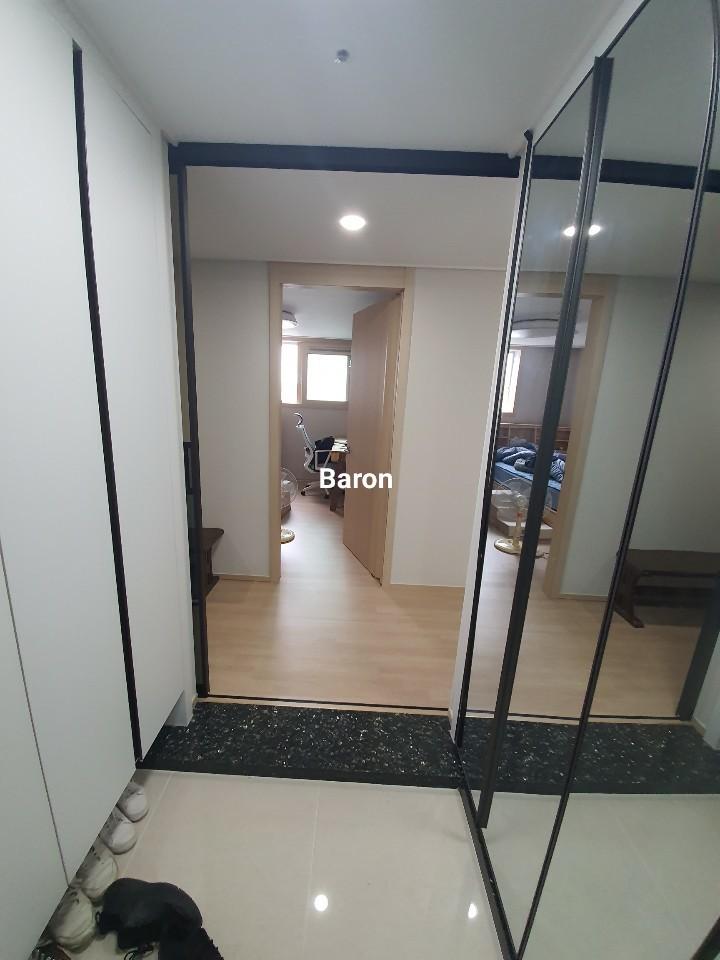 화이트 타일 바닥 위로 설치 중인 블랙 프레임 유리문