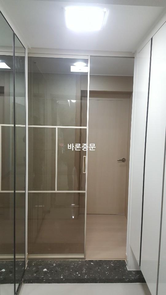 베이지색 패널 벽면과 유리문이 설치된 복도