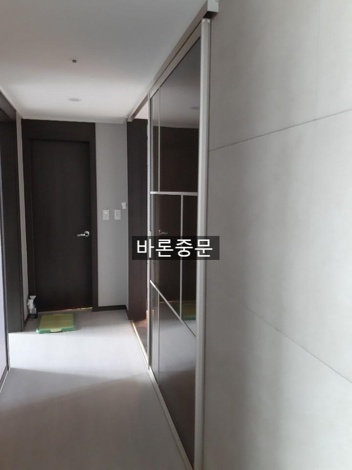 밝은 타일 바닥과 어두운 톤의 문이 대비되는 복도
