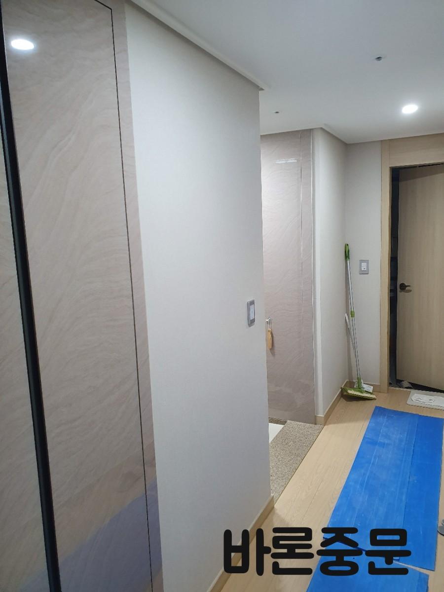 파란색 보호 테이프가 깔린 바닥과 목재 톤의 도어