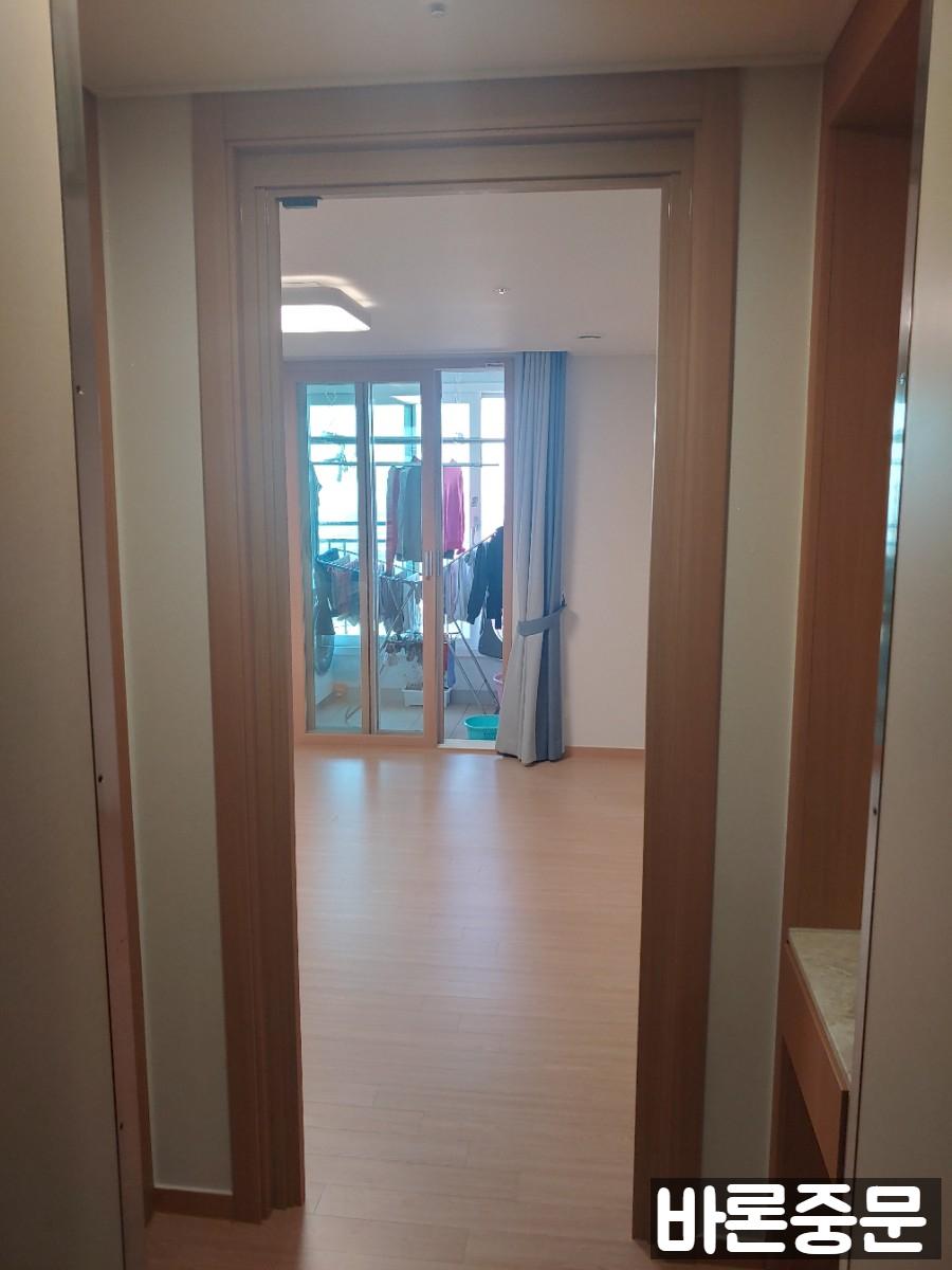 흰색 벽지와 나무 마루가 어우러진 공간의 목재 프레임 문