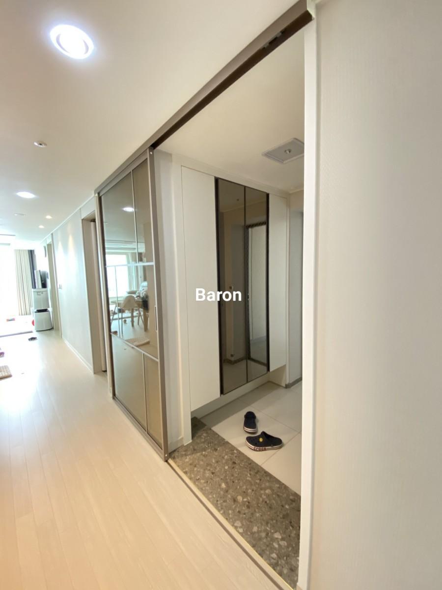 유리 도어와 화이트 수납장이 배치된 복도