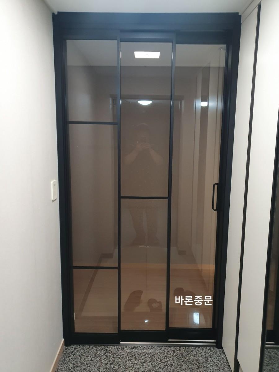 석재 바닥과 대비되는 블랙 프레임의 현관 모습