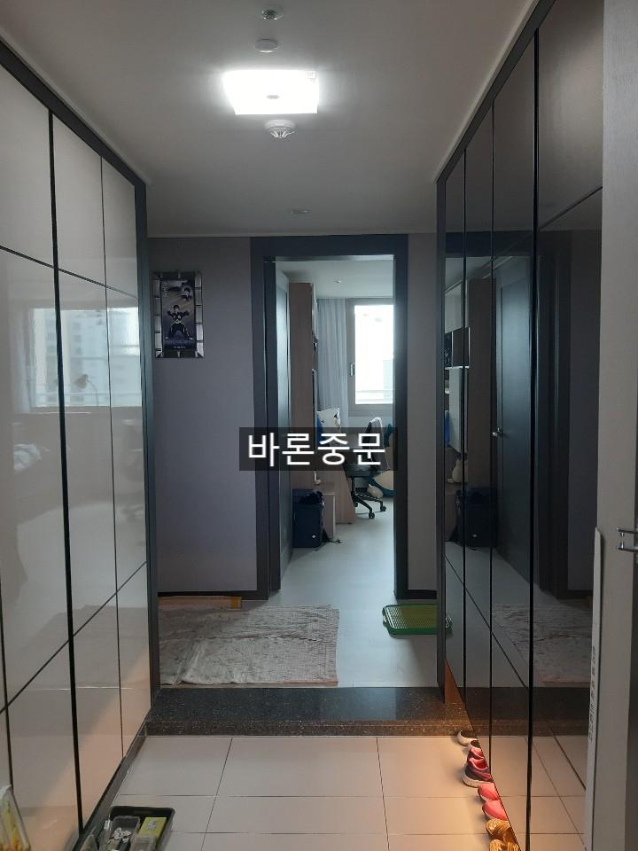 복도 공간, 양쪽에 유리문으로 된 수납장, 중앙에 흰색 타일 바닥, 뒤쪽에 문이 있는 공간, 바닥에 빨간색 신발이 놓여 있음