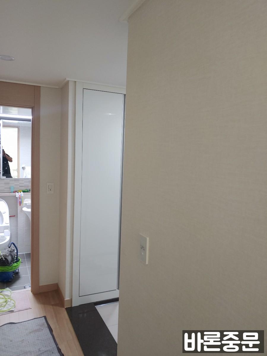 무광 화이트 수납장과 거울이 배치된 실내 모습