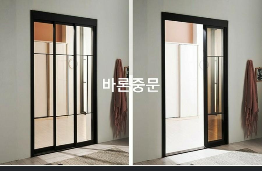 흰 벽과 목재 바닥재 사이에 설치된 검은색 프레임 도어