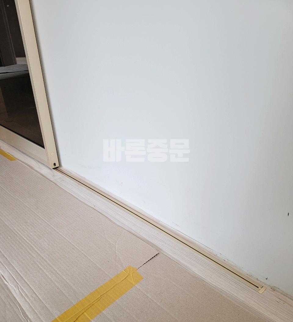 베이지색 바닥재 위에 설치된 금속 도어 트랙