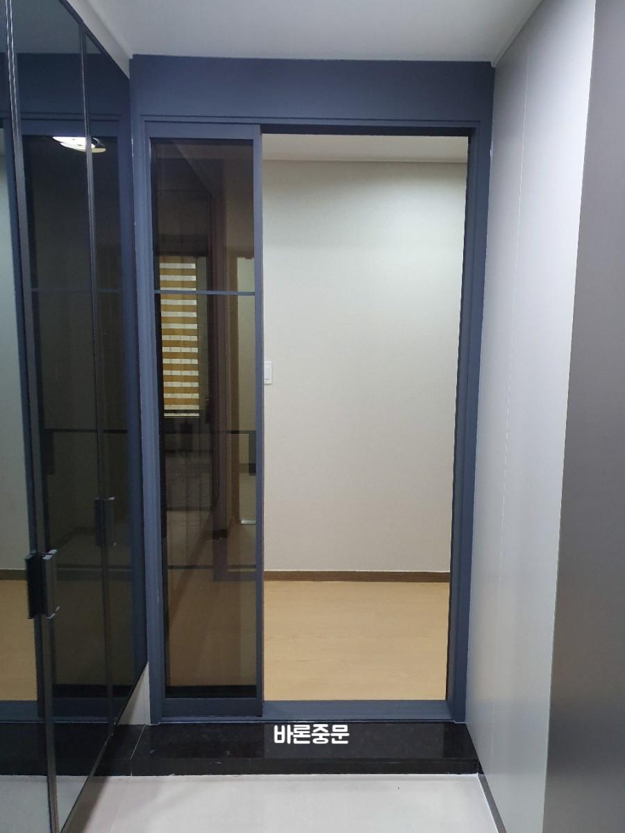 베이지색 벽과 목재 바닥 위 설치된 유리 도어