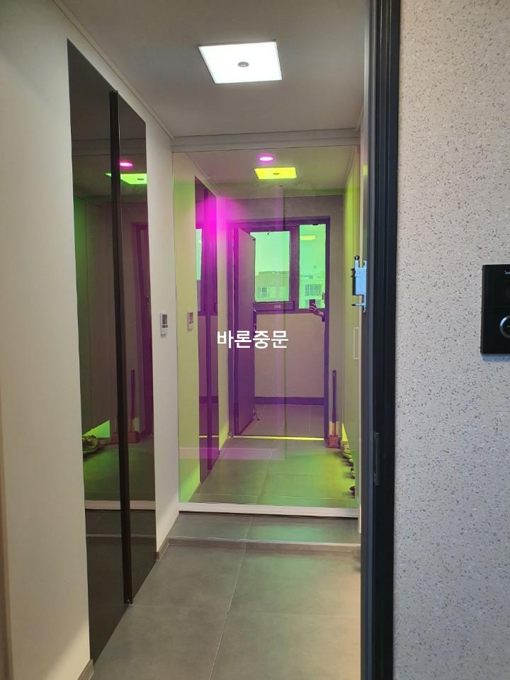 흰색 벽지와 회색 타일 사이의 유리문