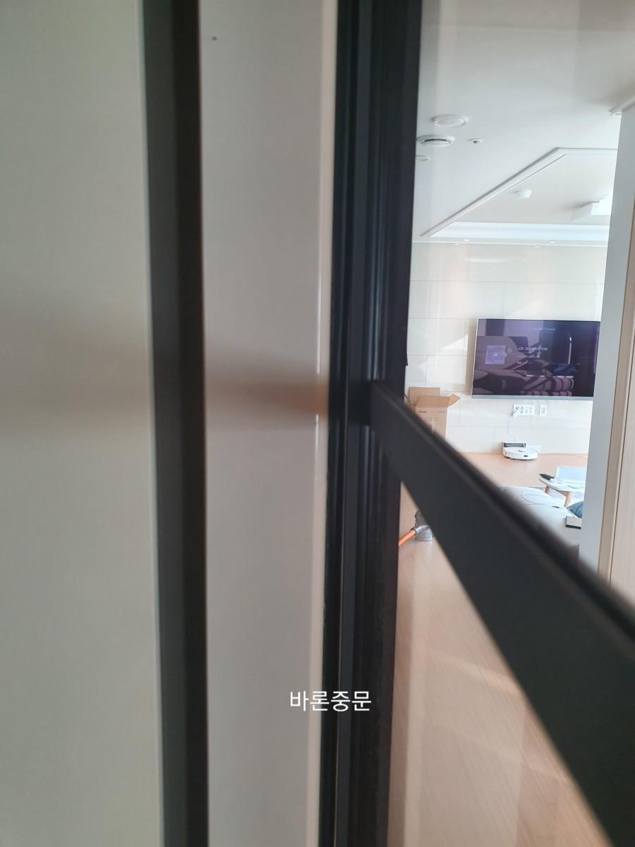 문이 열린 상태에서 보이는 흰색 타일 벽과 거실 내부