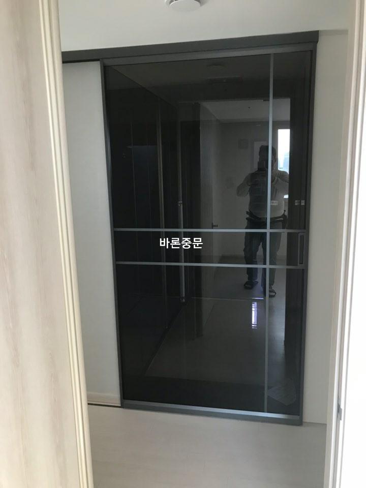 밝은 목재 마루와 대비되는 검은색 프레임 도어