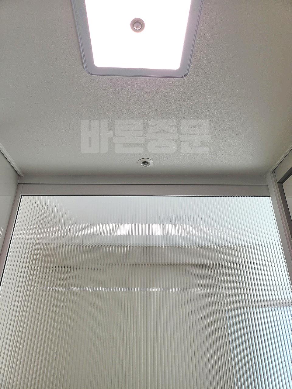 라인형 블라인드 창호와 천장 조명이 보이는 실내