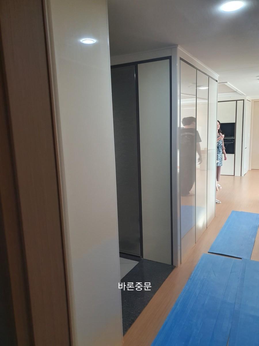 유리 도어가 설치된 화이트 수납장과 목재 바닥의 모습