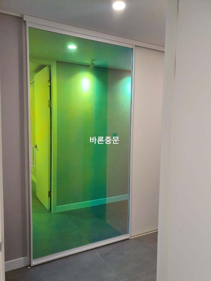유리문 너머로 노란색 벽이 보이는 복도