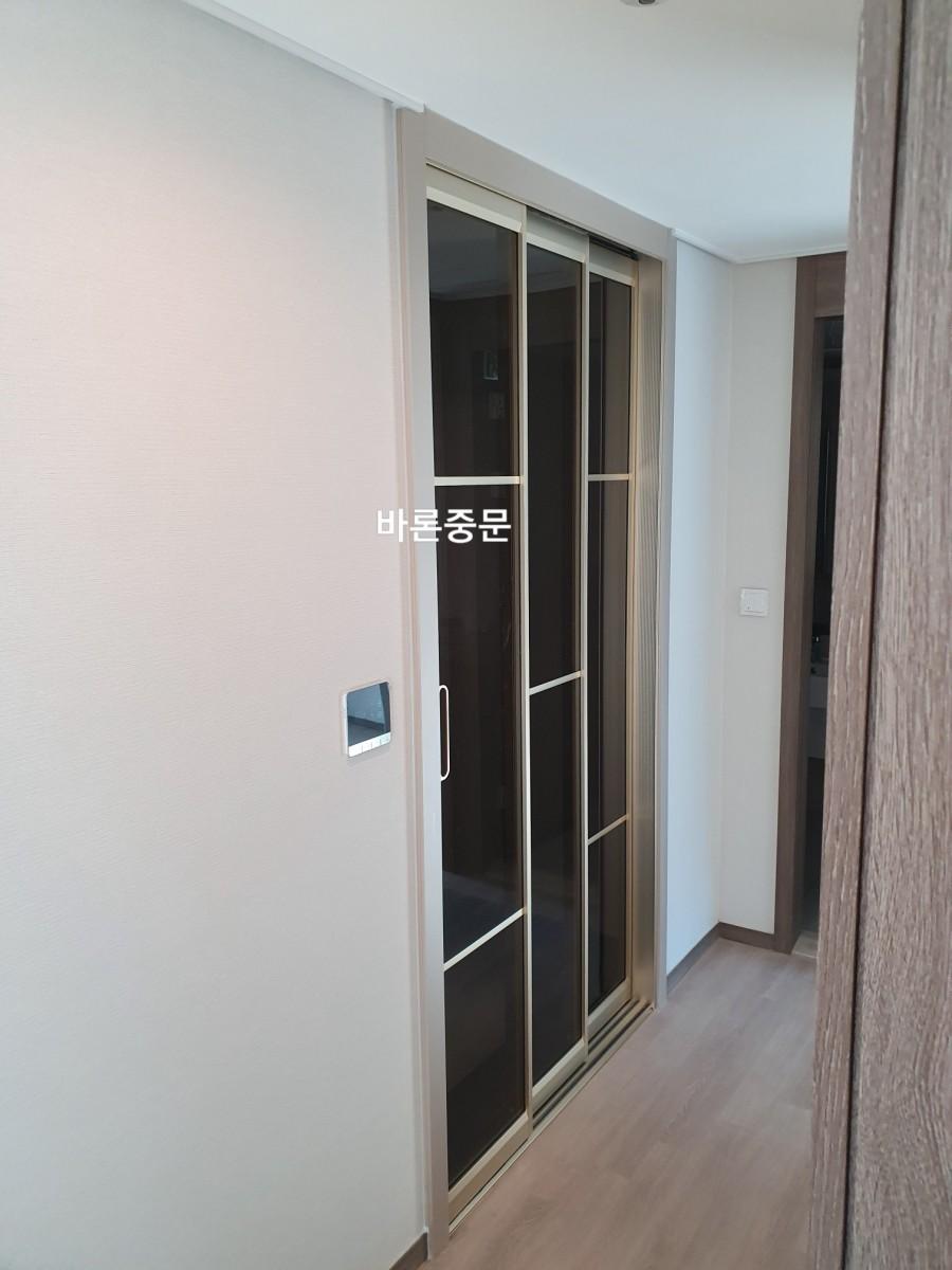 목재 마루와 흰색 벽지가 만나는 지점의 중문 설치 모습