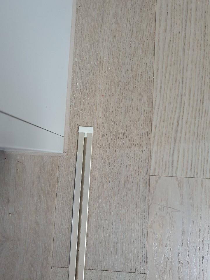 벽과 바닥 접합부에 설치된 흰색 프레임