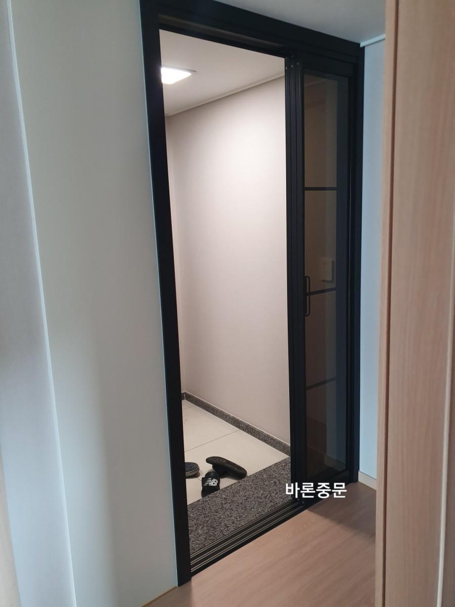 열린 중문 너머로 보이는 회색 석재 바닥의 현관