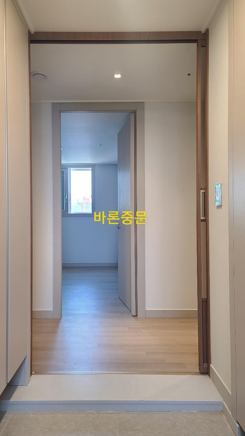 흰색 벽면과 나무 재질 문틀이 만나는 복도 지점