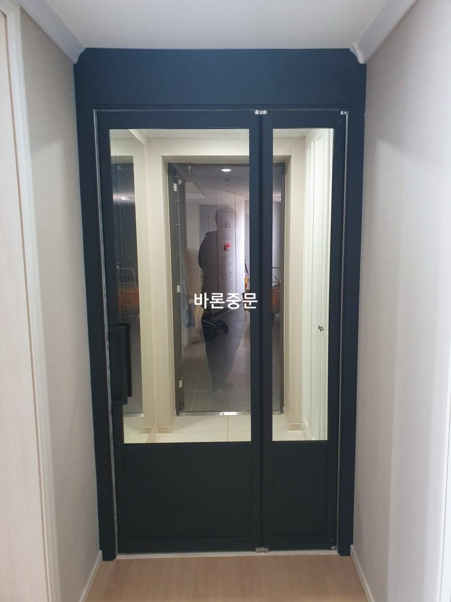 나무 바닥과 흰 벽면 사이에 설치된 유리문