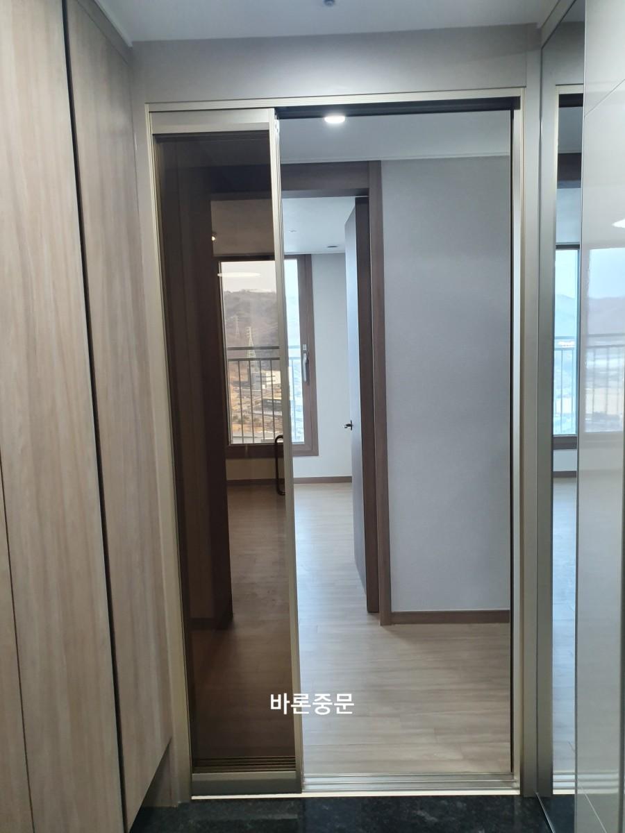 문이 열린 상태에서 보이는 목재 마루와 흰색 벽면