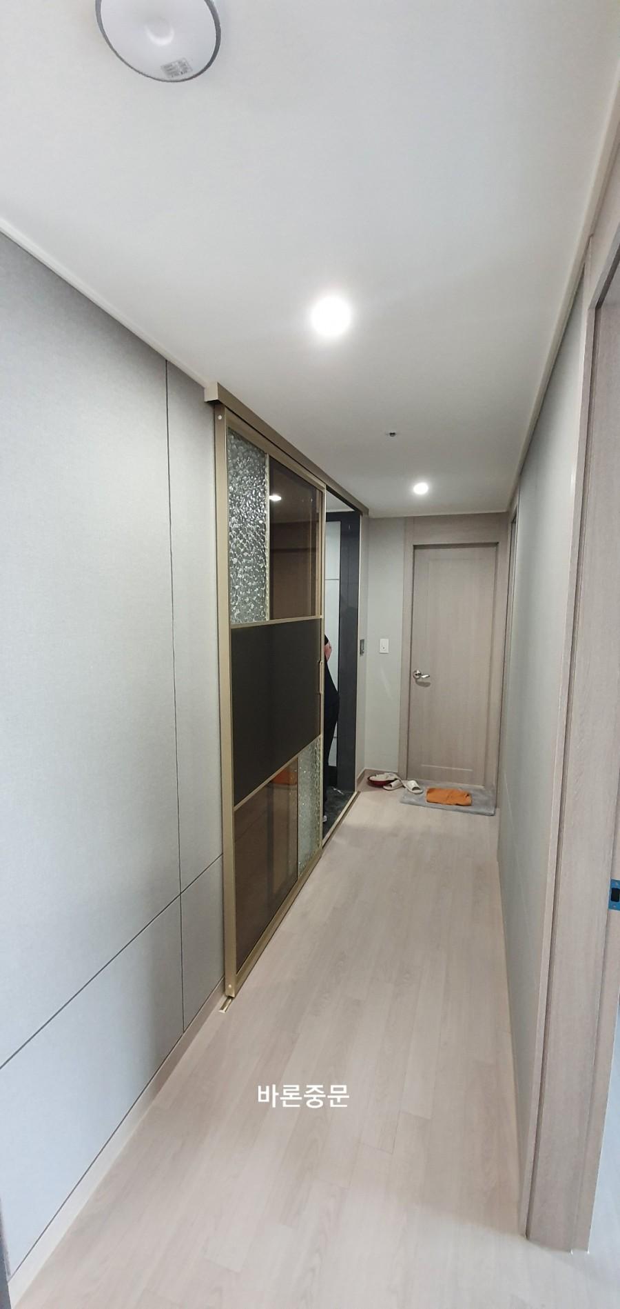 금색 프레임 수납장과 베이지색 마루가 보이는 복도