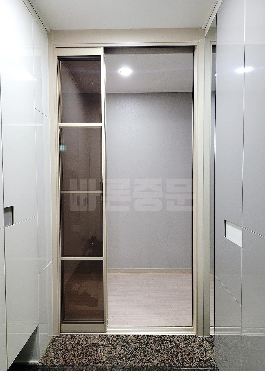 회색 유리 도어와 갈색 석재 바닥의 대비