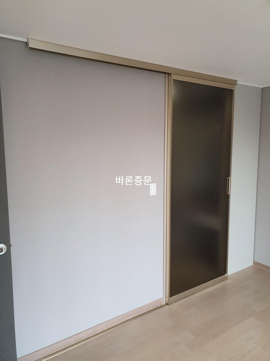 설치가 완료된 슬라이딩 도어와 회색 벽면의 조화