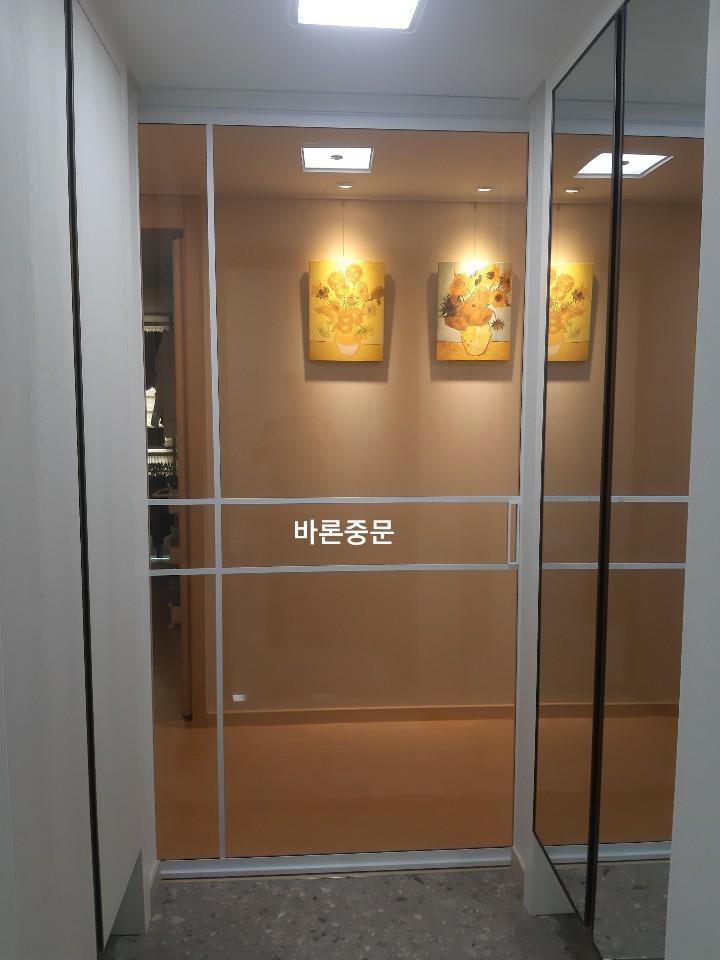 베이지색 벽면과 꽃 그림, 유리문이 보이는 복도 전경