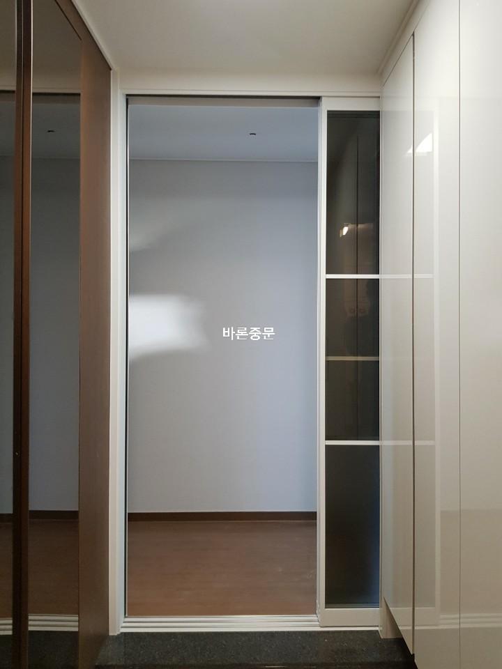 투명 유리 도어와 유리 패널 수납장이 배치된 공간