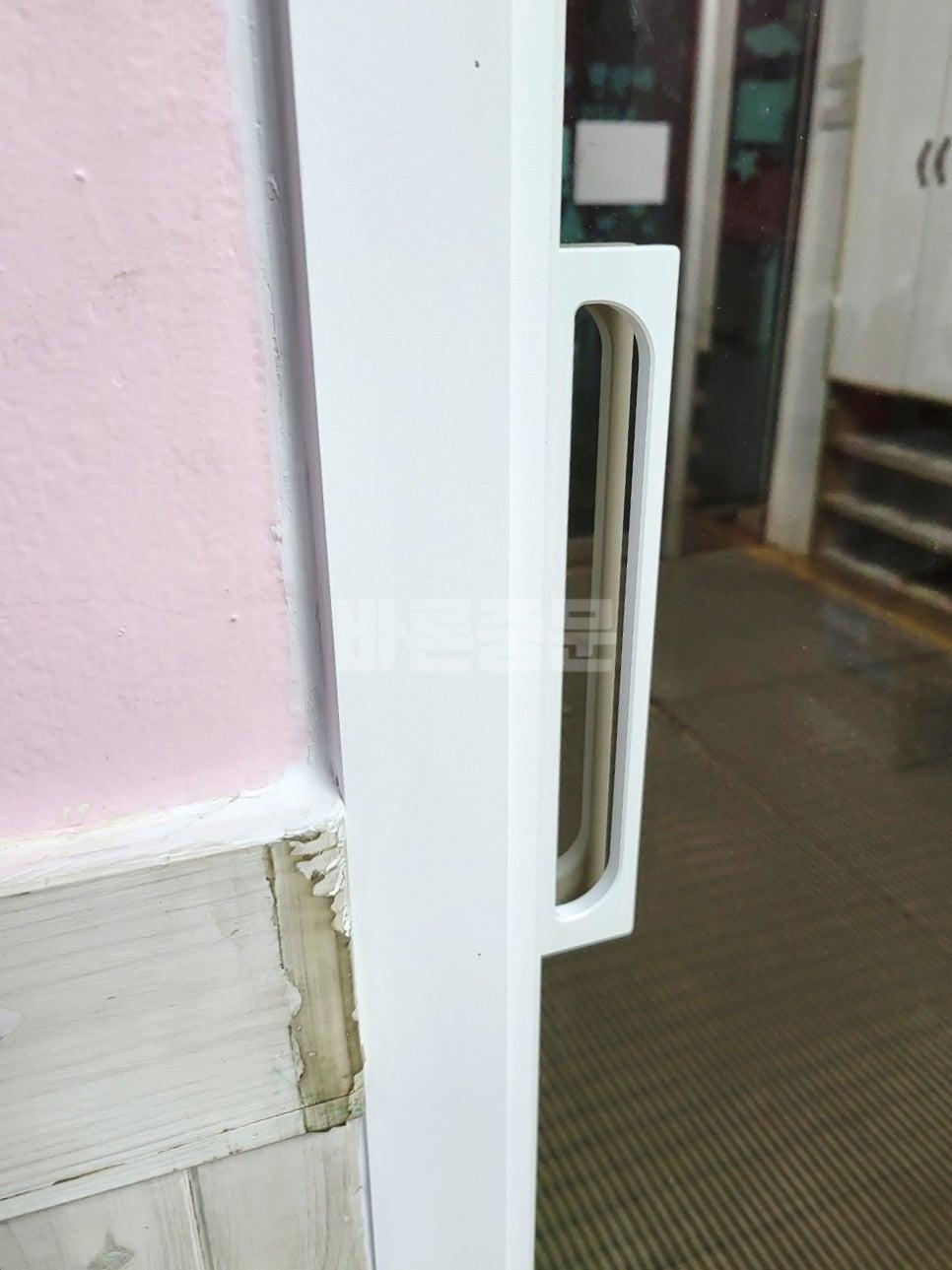 화이트 도어 핸들과 분홍색 벽면의 근접 모습