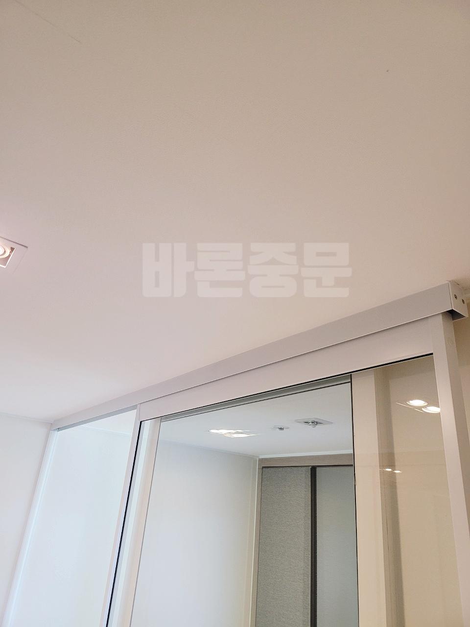 흰색 상판과 벽면이 보이는 공간의 유리 슬라이딩 도어