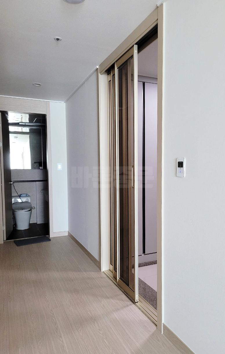 흰 벽과 목재 마루가 이어지는 복도의 정경