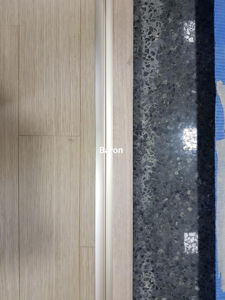 목재 패널과 흑색 석재 바닥의 접합부 디테일