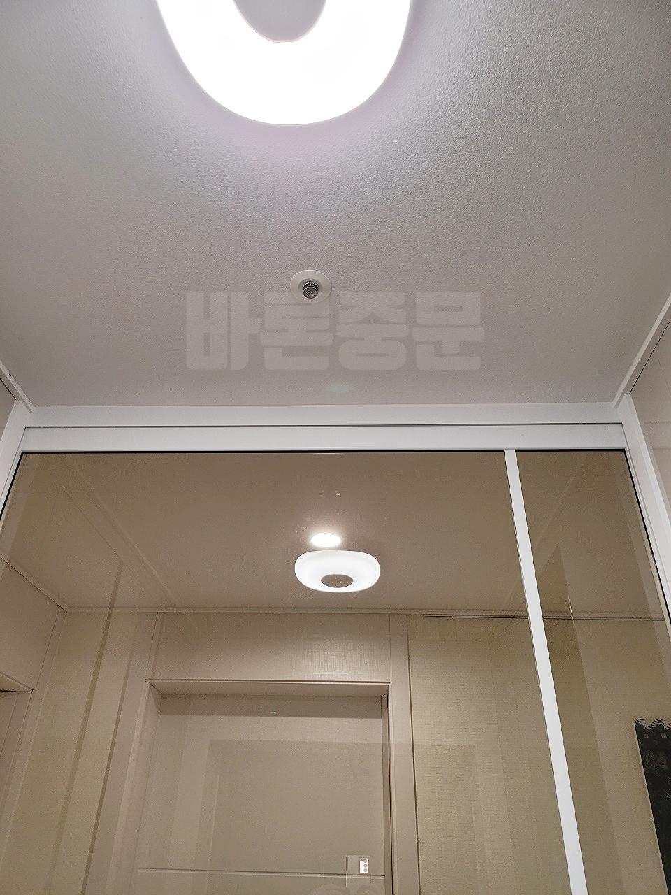 천장 조명과 소방 설비 아래 고정된 화이트 프레임