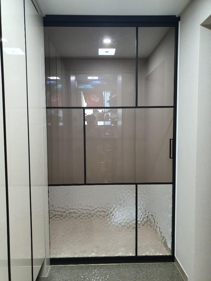 회색 타일 바닥과 블랙 프레임이 만나는 현관 모습