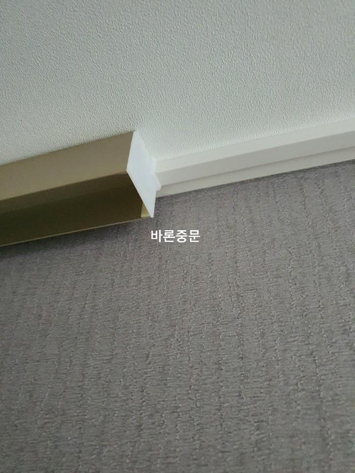 벽과 바닥 접합부에 적용된 금색 마감재 디테일