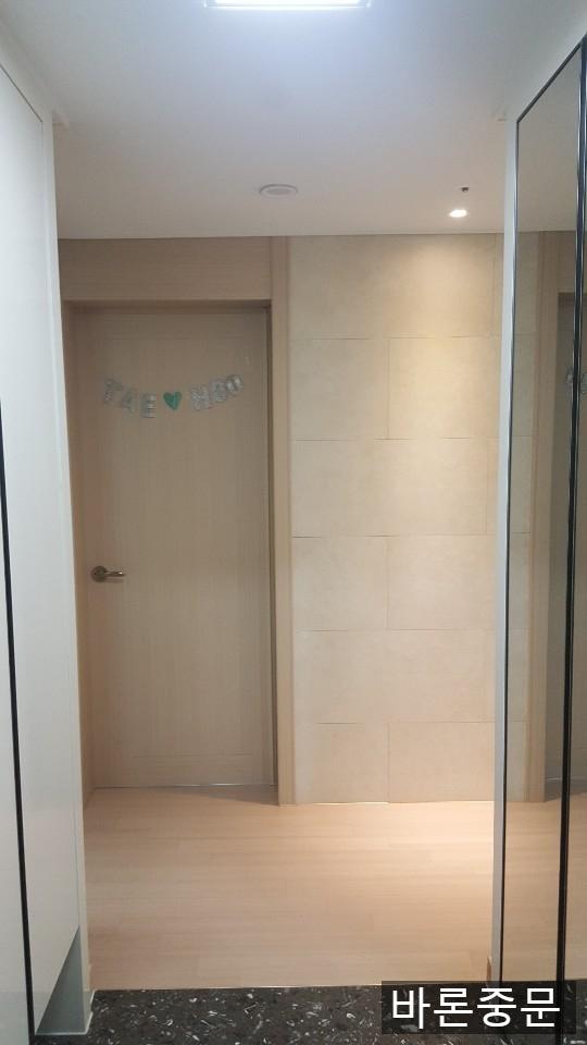베이지색 타일 벽면과 목재 바닥이 보이는 복도 시공 과정