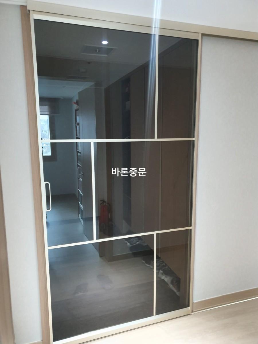 흰색 프레임의 유리 패널과 내부 수납장이 보이는 복도