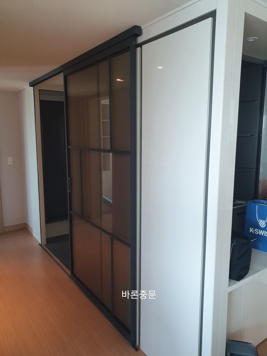 검은 테두리 유리 슬라이딩 도어가 설치된 복도 공간