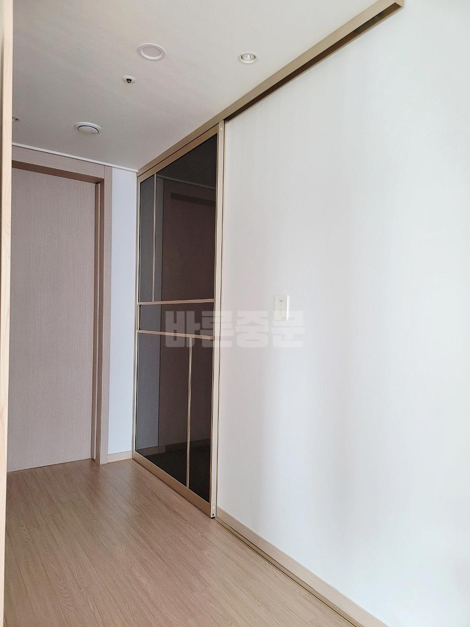우드톤 수납장과 투명 슬라이딩 도어가 설치된 공간