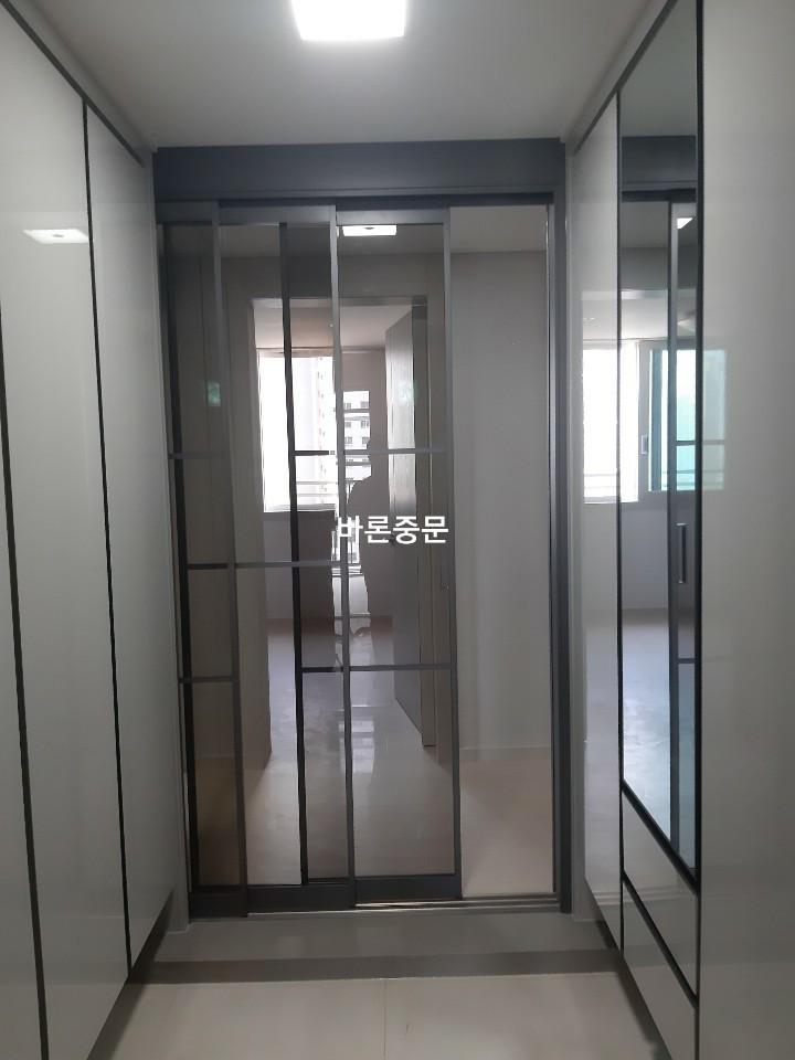 밝은 타일 바닥과 대비되는 블랙 프레임의 중문