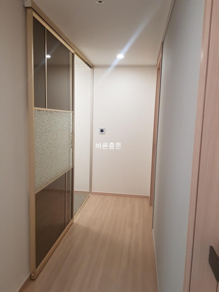 화이트 벽지와 목재 마루가 어우러진 복도 시공 모습