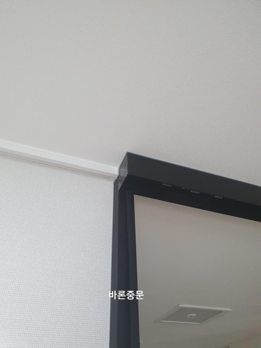 천장 마감선과 밀착된 블랙 프레임 상단