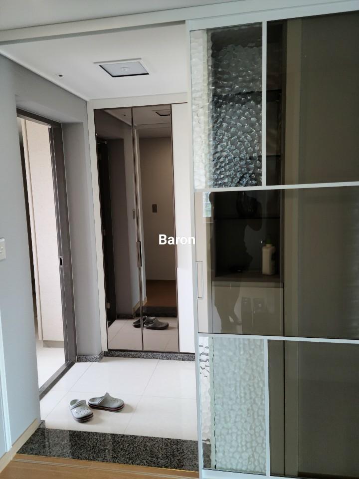 흰색 타일 바닥과 석재 패널 수납장이 있는 현관