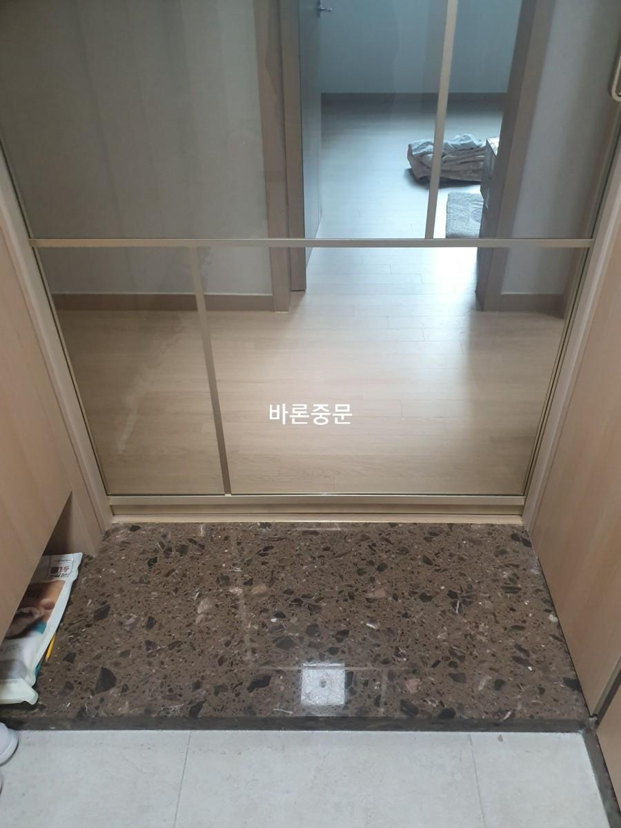 갈색 석재 바닥 위로 설치된 현관 유리문