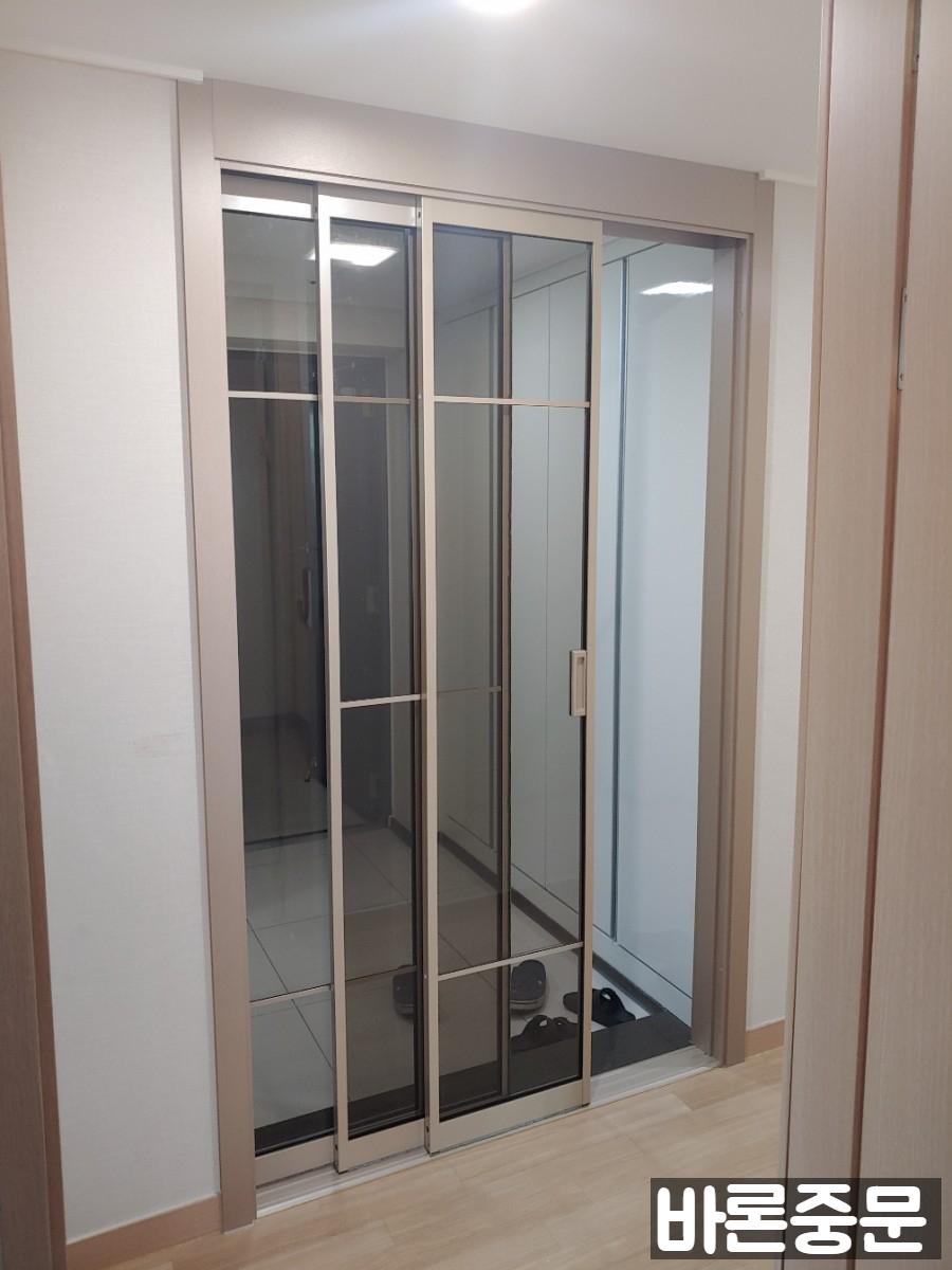 베이지색 벽면과 띠 분할 유리가 적용된 중문