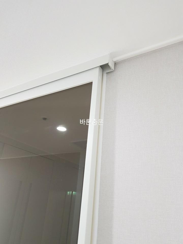 흰색 벽면과 맞닿은 슬라이딩 도어 상단 구조물