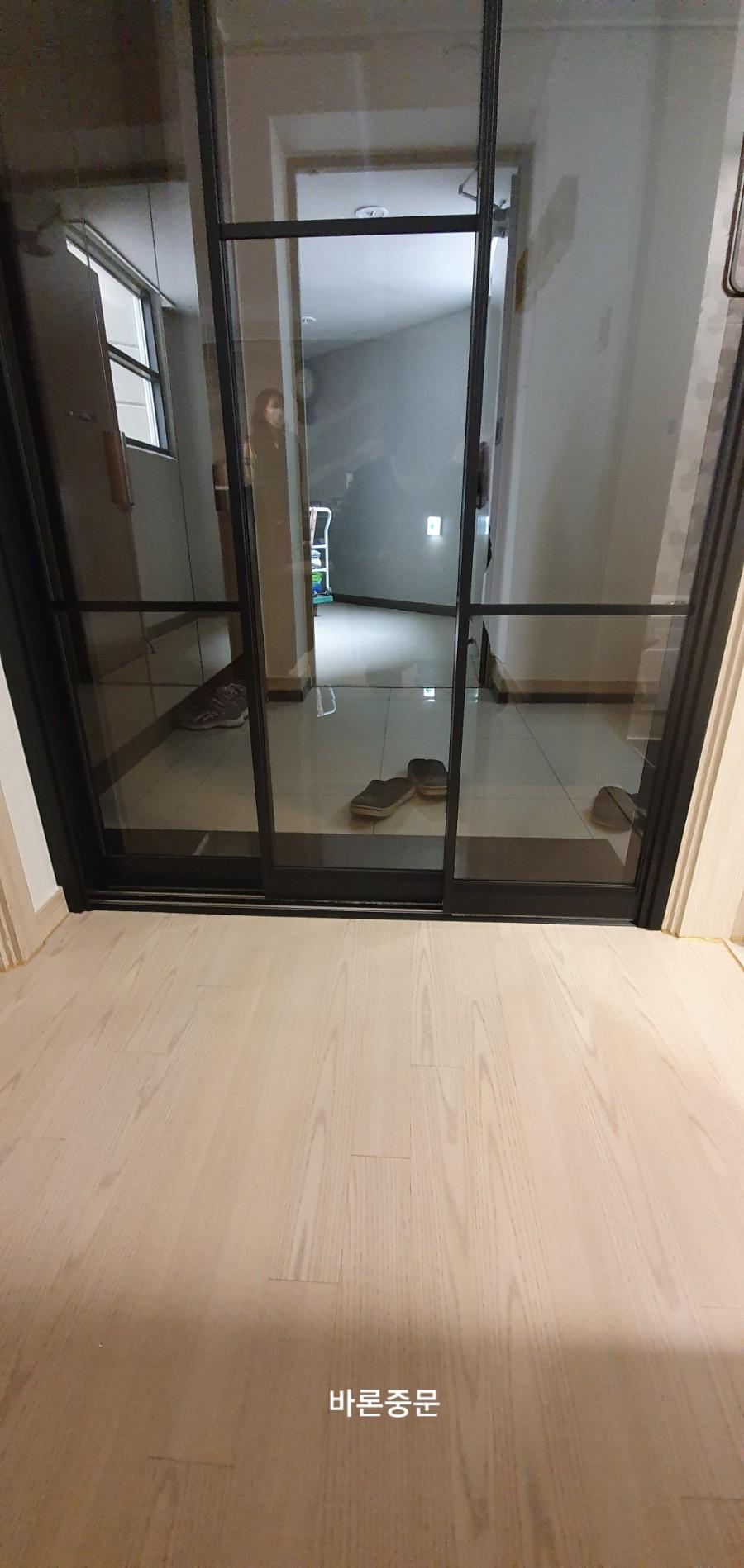 목재 마루와 타일 바닥을 가르는 블랙 유리문