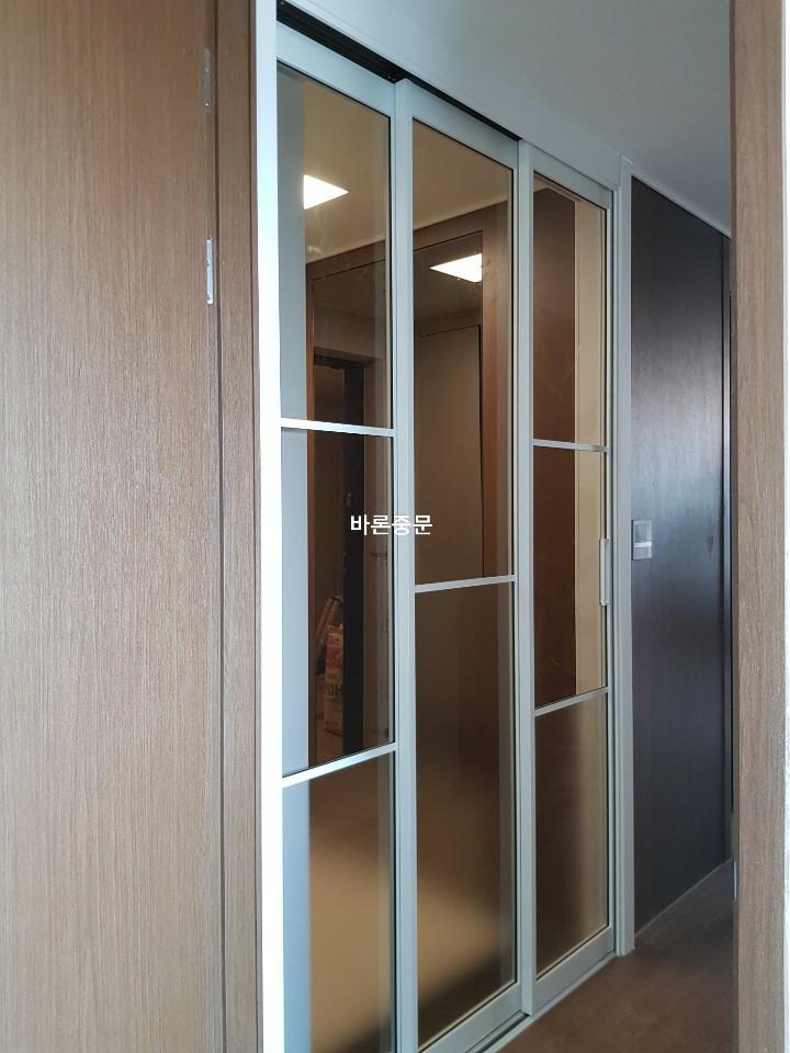 투명 유리 패널 도어와 나무 재질 벽면의 조화